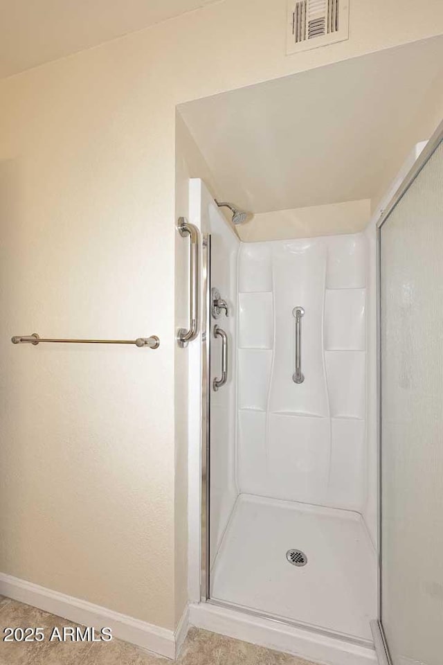 bathroom with a shower stall, visible vents, and baseboards