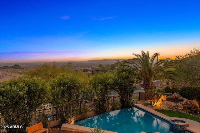 13621 E Aster Dr, Scottsdale, AZ 85259 - pool at dusk featuring a pool with connected hot tub and fence