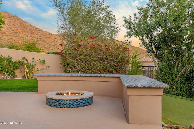 13621 E Aster Dr, Scottsdale, AZ 85259 - patio terrace at dusk with an outdoor fire pit, a fenced backyard, and a mountain view