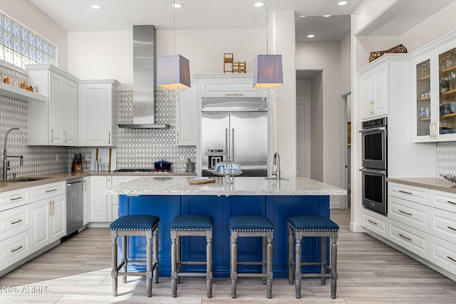 13621 E Aster Dr, Scottsdale, AZ 85259 - kitchen featuring wall chimney range hood, white cabinets, a sink, and appliances with stainless steel finishes