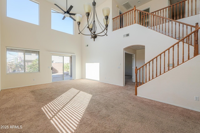 unfurnished living room featuring arched walkways, carpet flooring, visible vents, baseboards, and stairway