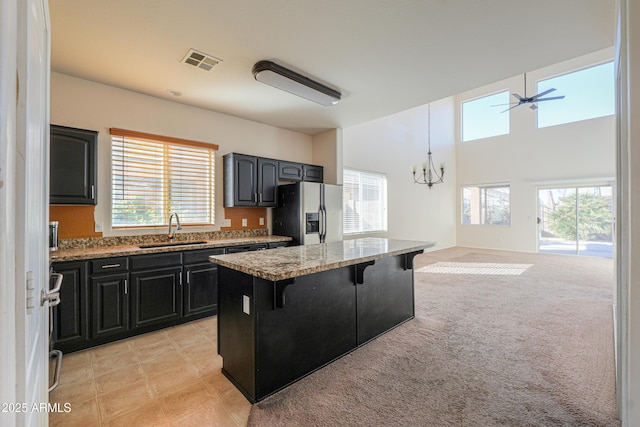 kitchen featuring stainless steel fridge, a breakfast bar area, open floor plan, a center island, and a sink