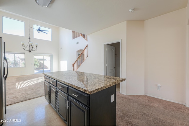 kitchen featuring a notable chandelier, light colored carpet, open floor plan, a kitchen island, and dark cabinetry