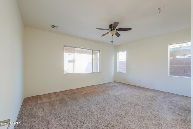 spare room featuring ceiling fan, visible vents, and light colored carpet