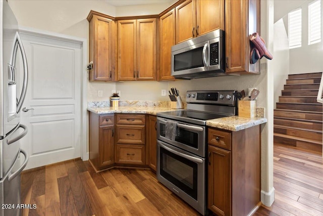 kitchen featuring light stone countertops, wood-type flooring, and appliances with stainless steel finishes