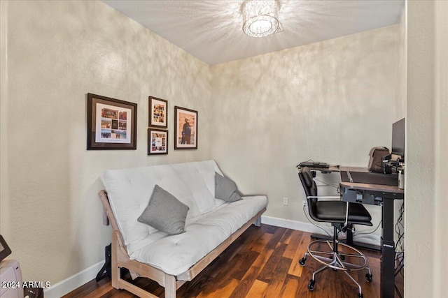 home office with dark wood-type flooring and a notable chandelier