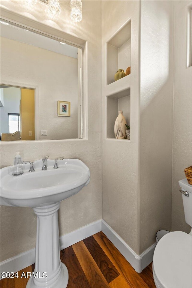 bathroom with hardwood / wood-style floors, built in shelves, and toilet