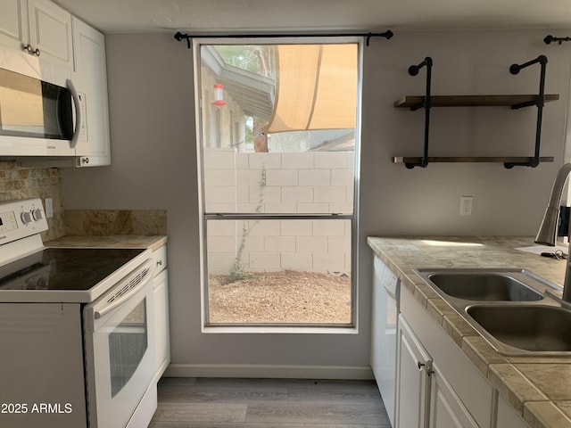 kitchen with white appliances, tile counters, sink, and white cabinets