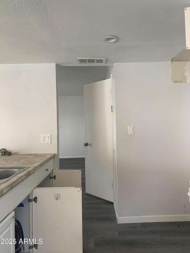 kitchen with sink, dark wood-type flooring, white cabinets, and a textured ceiling