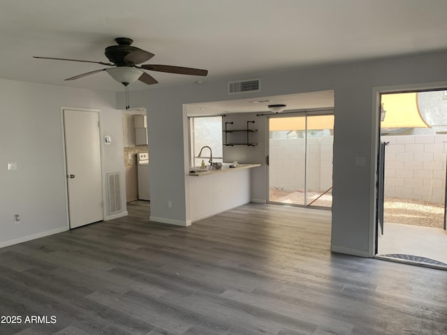 unfurnished living room featuring hardwood / wood-style flooring, sink, ceiling fan, and washer / clothes dryer