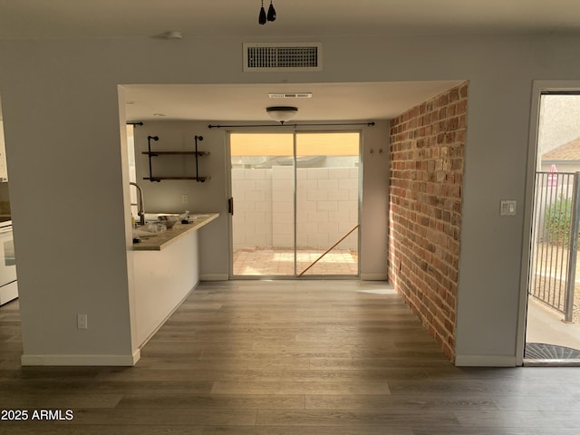 hall with brick wall and dark hardwood / wood-style flooring