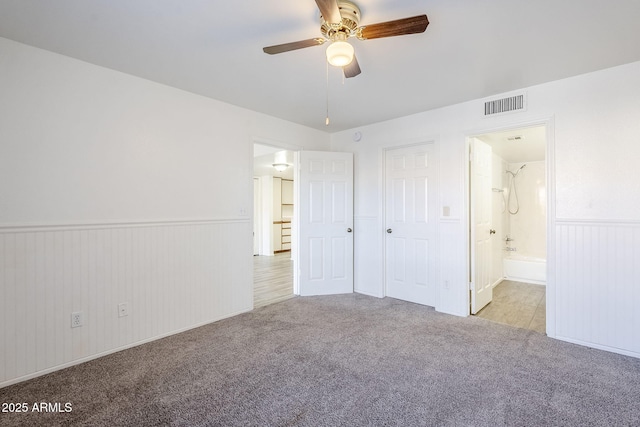 unfurnished bedroom featuring ceiling fan, light carpet, and ensuite bath