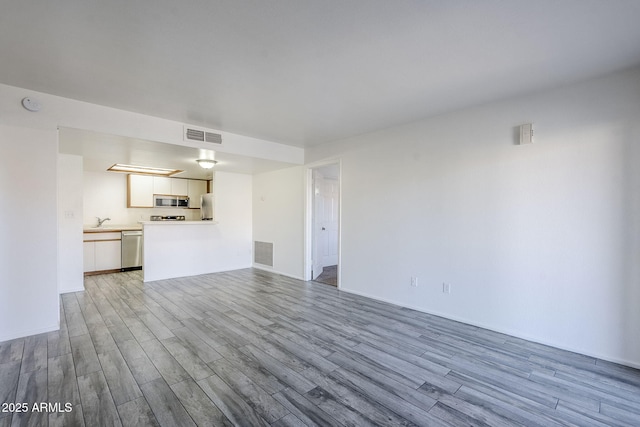 unfurnished living room featuring sink and light hardwood / wood-style flooring