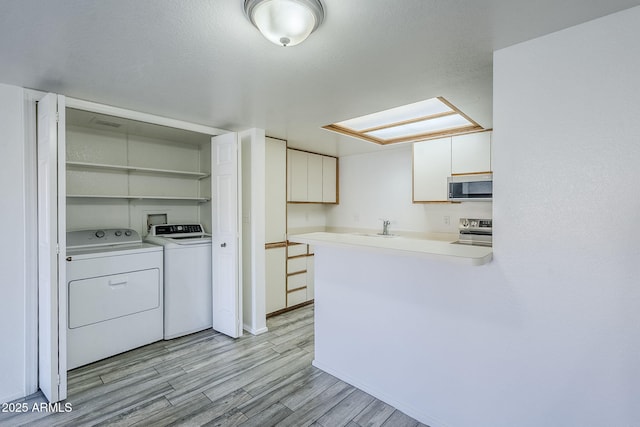 kitchen with sink, light hardwood / wood-style flooring, appliances with stainless steel finishes, white cabinetry, and separate washer and dryer