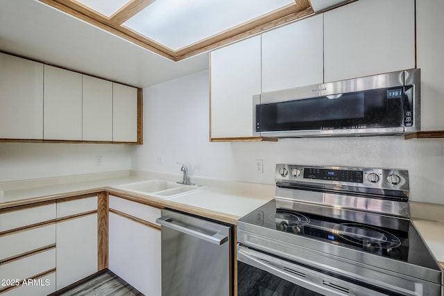 kitchen featuring appliances with stainless steel finishes, sink, white cabinets, and light hardwood / wood-style flooring