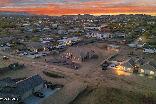 aerial view at dusk featuring a mountain view and a residential view