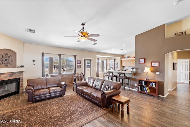 living area featuring a wealth of natural light, visible vents, wood finished floors, and a fireplace