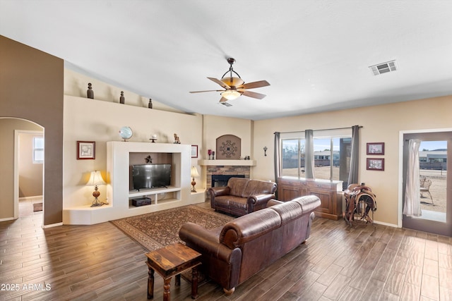 living area with vaulted ceiling, arched walkways, visible vents, and dark wood-style flooring