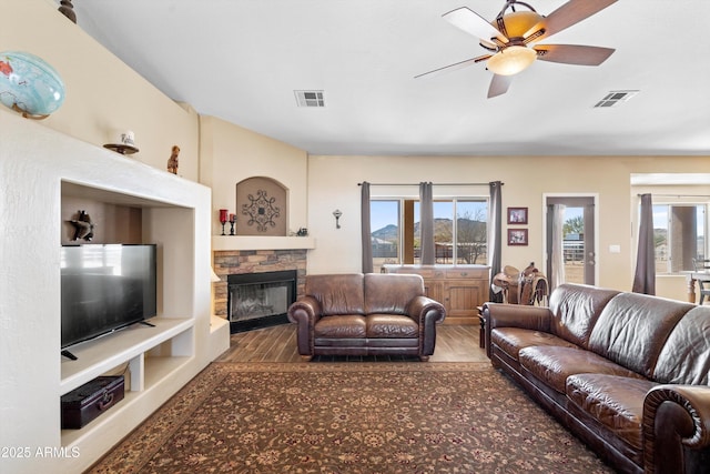 living area featuring a wealth of natural light, visible vents, and wood finished floors