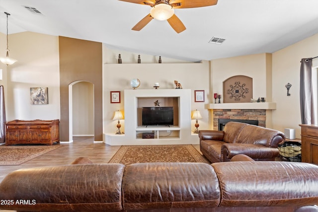 living room with visible vents, lofted ceiling, wood finished floors, and a fireplace