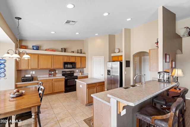 kitchen featuring visible vents, black appliances, a sink, a peninsula, and light countertops