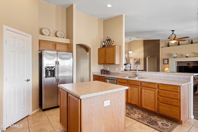 kitchen with a peninsula, arched walkways, appliances with stainless steel finishes, and a sink