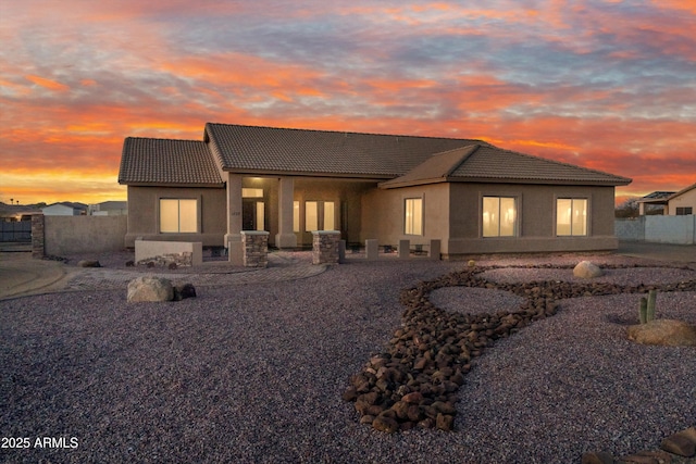 back of property featuring a patio, a tile roof, fence, and stucco siding