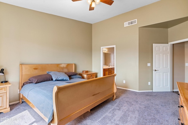 carpeted bedroom with visible vents, baseboards, ensuite bathroom, and a ceiling fan