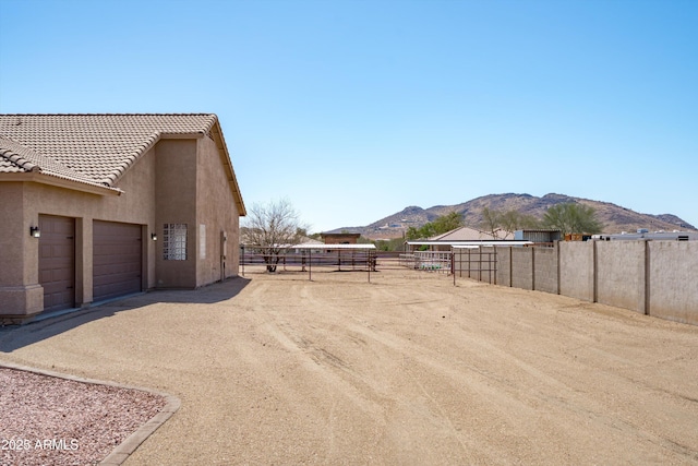 view of yard with a mountain view, a garage, driveway, and fence