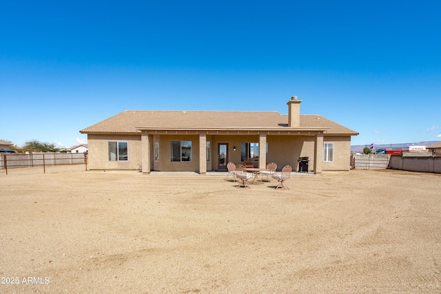 rear view of house with a patio area, stucco siding, a chimney, and a fenced backyard