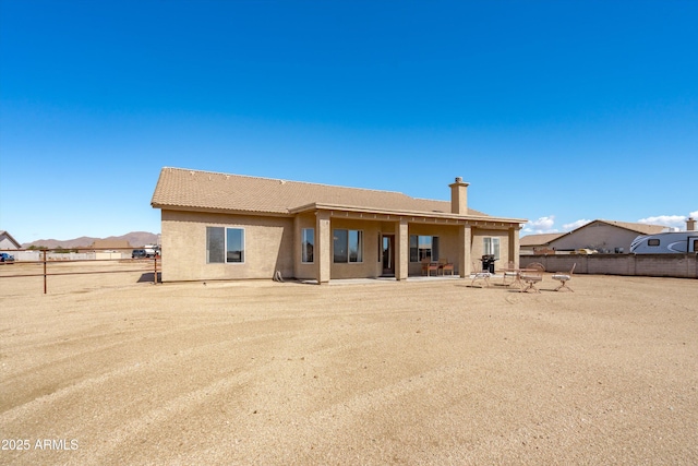 rear view of property with a patio area, fence, and stucco siding