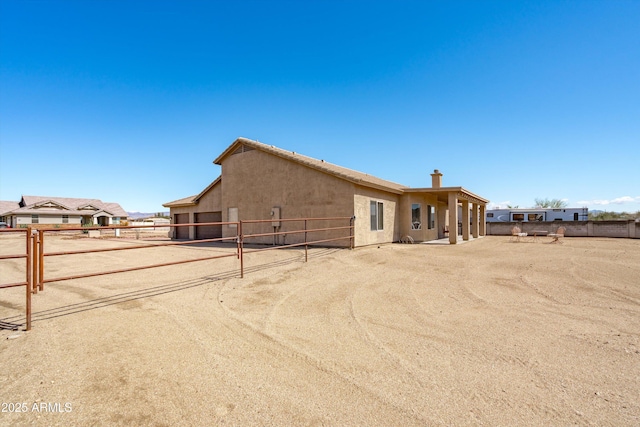 rear view of property with stucco siding and fence