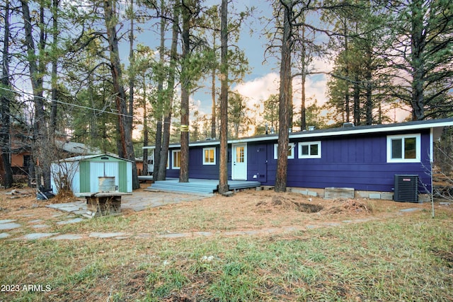 view of front of property featuring board and batten siding, an outbuilding, cooling unit, and a shed