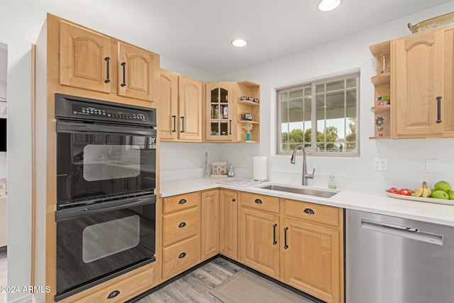 kitchen with light wood-type flooring, stainless steel dishwasher, double oven, sink, and light brown cabinets