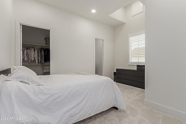 carpeted bedroom with a walk in closet and a closet