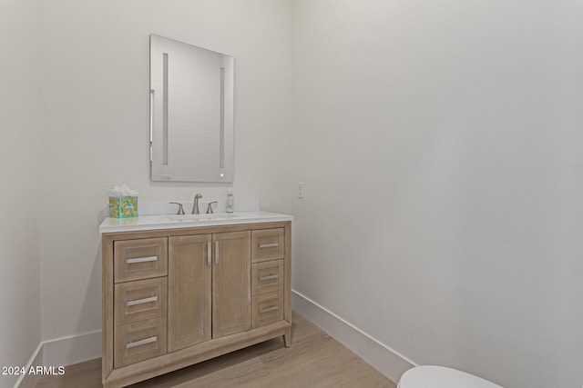 bathroom with hardwood / wood-style flooring, vanity, and toilet