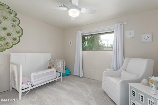 carpeted bedroom featuring ceiling fan and a nursery area