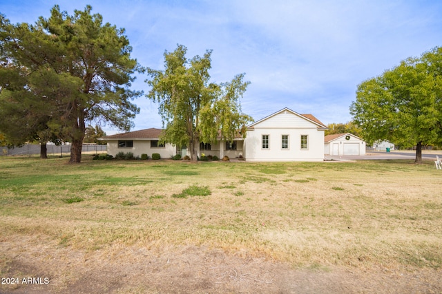 view of front facade featuring a garage, an outdoor structure, and a front lawn