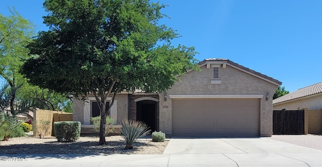 view of front facade featuring stucco siding, concrete driveway, an attached garage, and fence