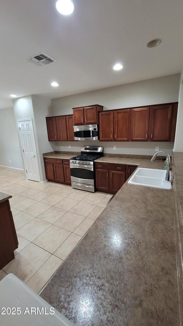 kitchen with appliances with stainless steel finishes, a sink, light tile patterned floors, and recessed lighting
