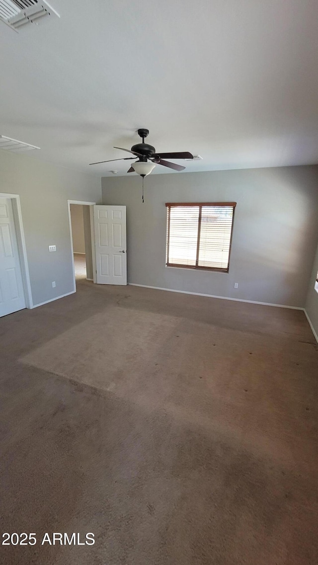 carpeted spare room featuring ceiling fan and baseboards