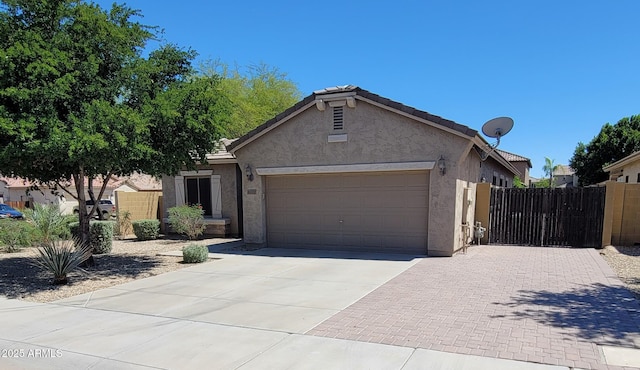 ranch-style house featuring driveway, stucco siding, an attached garage, and fence