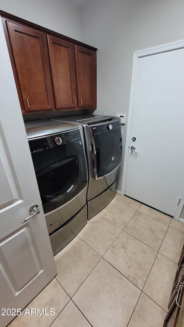 laundry area with washer and clothes dryer, cabinet space, and light tile patterned flooring