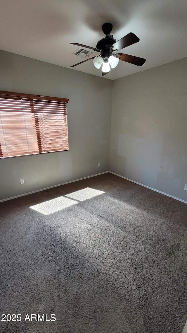 carpeted empty room featuring ceiling fan and baseboards