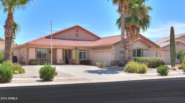 mediterranean / spanish home with a garage, concrete driveway, central AC, and stucco siding