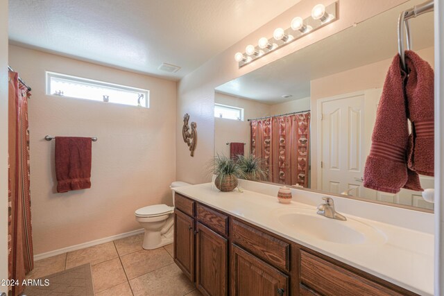 bathroom featuring tile patterned floors, toilet, vanity, and a healthy amount of sunlight