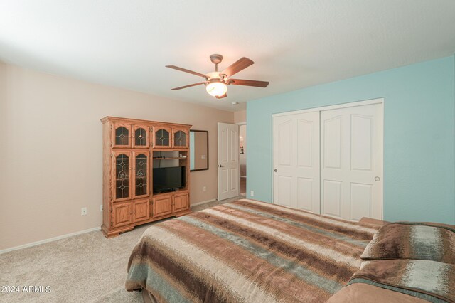 carpeted bedroom with ceiling fan and a closet