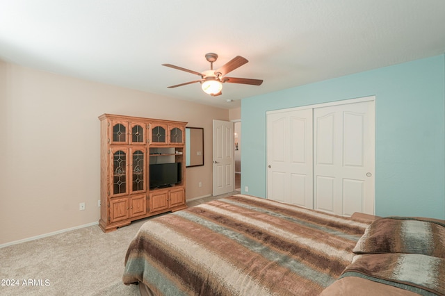 bedroom featuring baseboards, ceiling fan, a closet, and light colored carpet