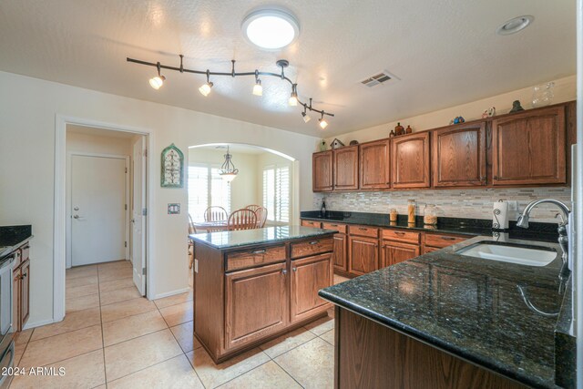 kitchen featuring backsplash, sink, rail lighting, a center island, and light tile patterned flooring