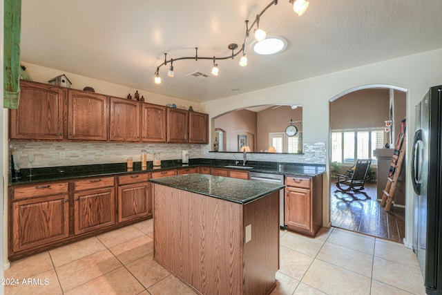 kitchen featuring light tile patterned floors, a kitchen island, a sink, and freestanding refrigerator